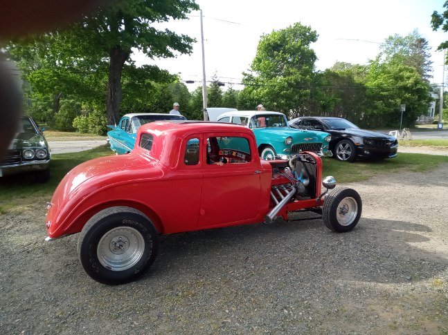 Red hot rod with classic cars in the background